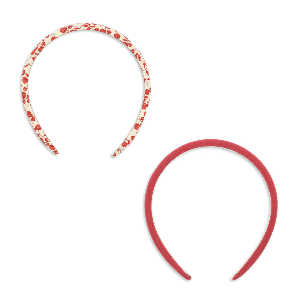 Two headbands with fabric covers, one with a red floral pattern and the other solid pink, isolated on a white background
